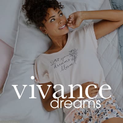 vivance dreams – Frau in T-Shirt mit Aufdruck „Let your dreams bloom“ liegt entspannt auf dem Bett