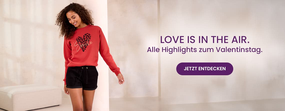 LOVE IS IN THE AIR. Alle Highlights zum Valentinstag. Frau in rotem Pullover und schwarzen Shorts im Raum. JETZT ENTDECKEN.