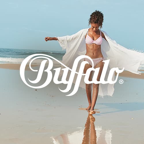 Buffalo Logo vor Frau im Bikini mit offenem Strandkimono, die barfuß am Meer entlangläuft