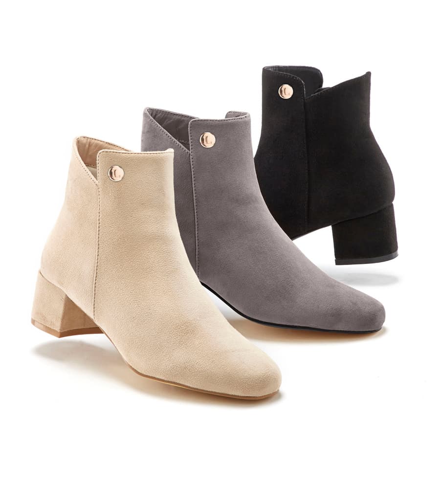 Drei knöchelhohe Stiefeletten mit Blockabsatz in Beige, Grau und Schwarz nebeneinander aufgestellt